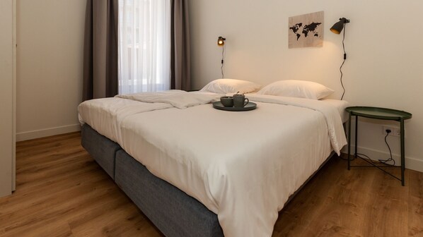 A neatly arranged bedroom with a bed, bedside tables, and a world map on the wall. - The old warehouse: a completely renovated apartment in the center of Leiden (Leiden)