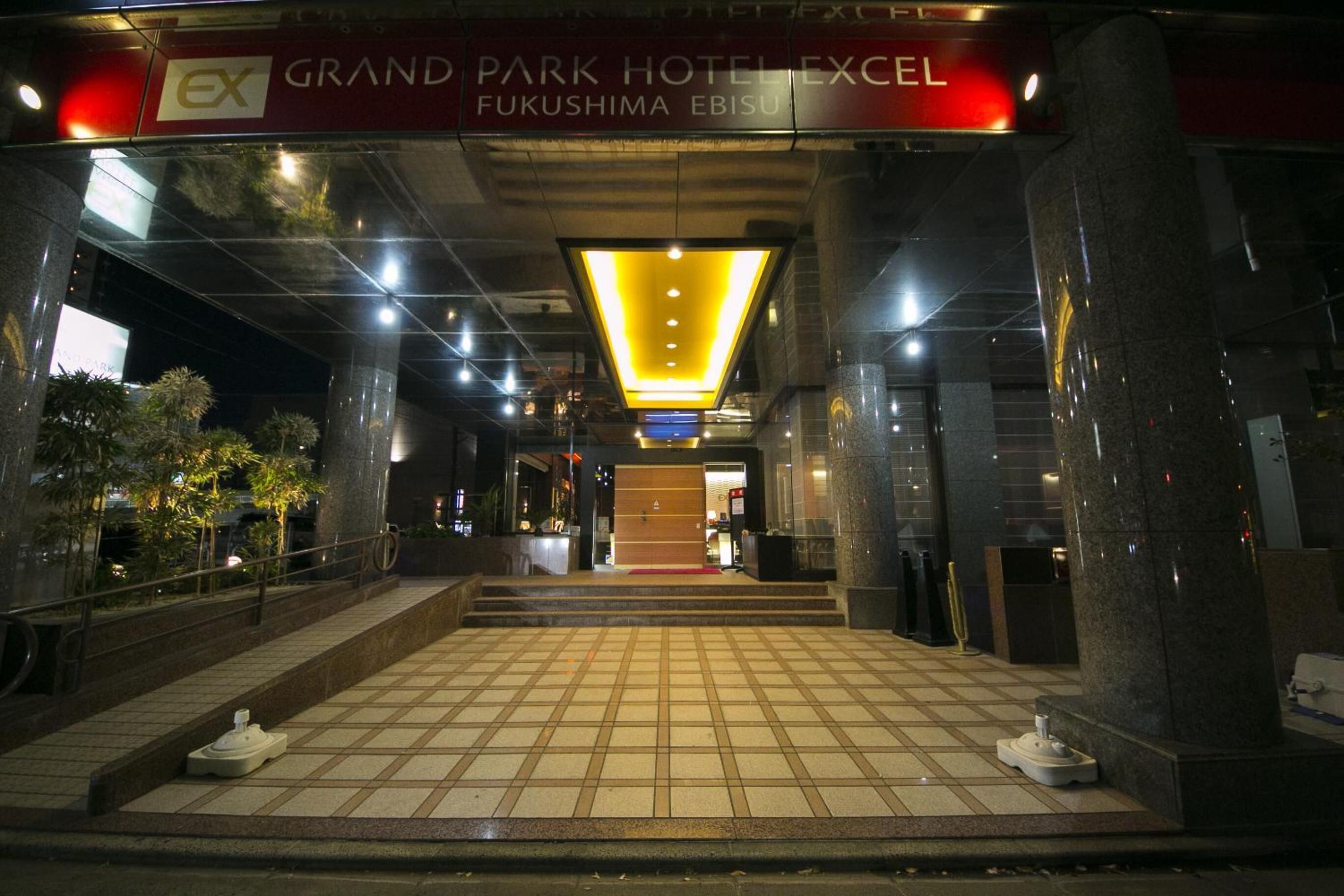The entrance to Grand Park Hotel Ex with a tiled floor and a bright overhead light.