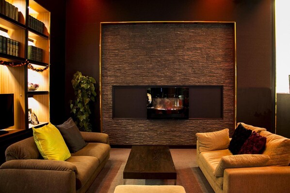 A cozy living room with a fireplace, two sofas, a coffee table, and a bookshelf.