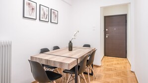 A dining area with a wooden table, black chairs, and a vase with flowers. There are framed pictures on the wall and a door in the background. - Modern Design Apartment Near Acropolis 2 (Athens)