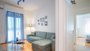 A modern living room with a sectional sofa, a glass coffee table, and a lamp. - Modern Design Apartment Near Acropolis 2 (Athens)