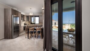A modern kitchen with a built-in refrigerator, wooden cabinets, and a dining area with a table and chairs. - Villa Stellina, elegant villa, full privacy (Chania)