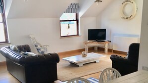 A modern living room with a sofa, a dining table, and a TV.