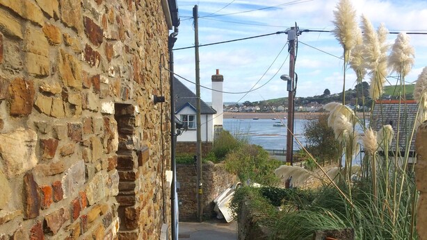 A narrow stone staircase leading to a beachside area with a view of the sea and boats.