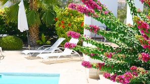 A poolside area with white lounge chairs and a pool.