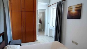 Un dormitorio con cama, armario y baño visible a través de una puerta abierta.