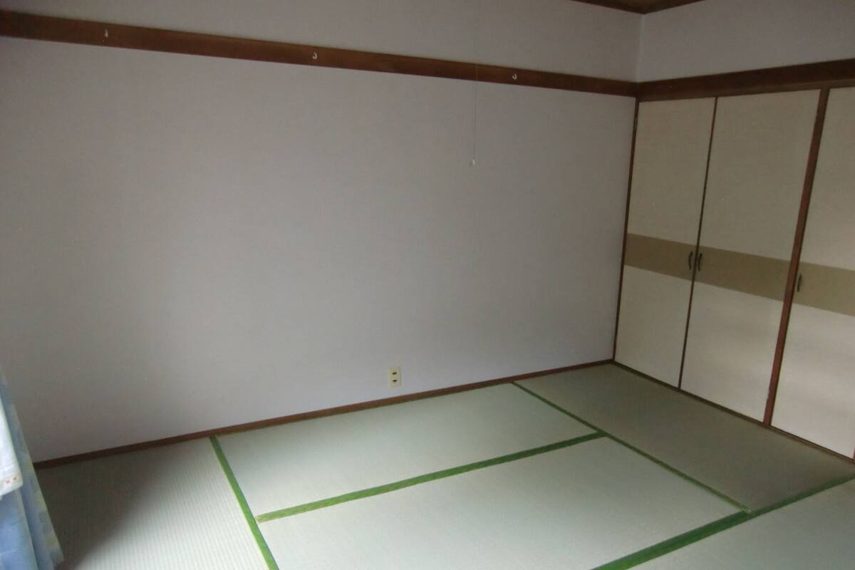 A room with tatami flooring, a shoji screen door, and a traditional Japanese-style wardrobe.