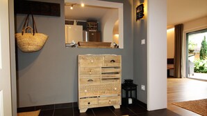 Een gang met een geweven mand, een houten dressoir en een spiegel aan de muur.