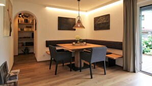 Een eetgedeelte met een houten tafel, vier stoelen, een bank en een hangende lamp.