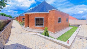 Uma casa de tijolos com telhado azul, um caminho de paralelepípedos e uma pequena área ajardinada.