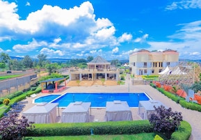 Um hotel com uma piscina grande, área de estar ao ar livre e um jardim bem cuidado.