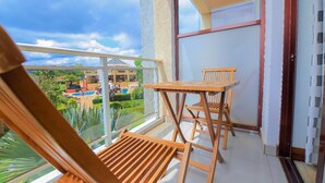 Varanda com mobiliário de madeira, porta de vidro e vista para uma piscina e vegetação.