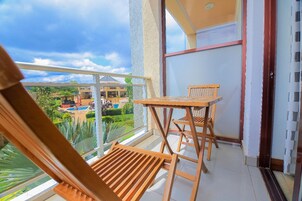 Varanda com mobiliário de madeira, porta de vidro e vista para uma piscina e vegetação.