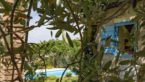 Un edificio in pietra con una porta blu e una piscina sullo sfondo.