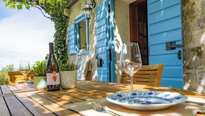 Un tavolo di legno con una bottiglia di vino, un bicchiere da vino e un piatto con decorazioni blu.