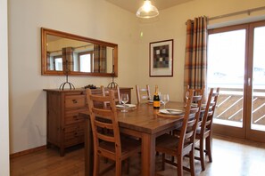 Un comedor con una mesa de madera dispuesta para cuatro personas, un aparador de madera y un espejo grande en la pared.