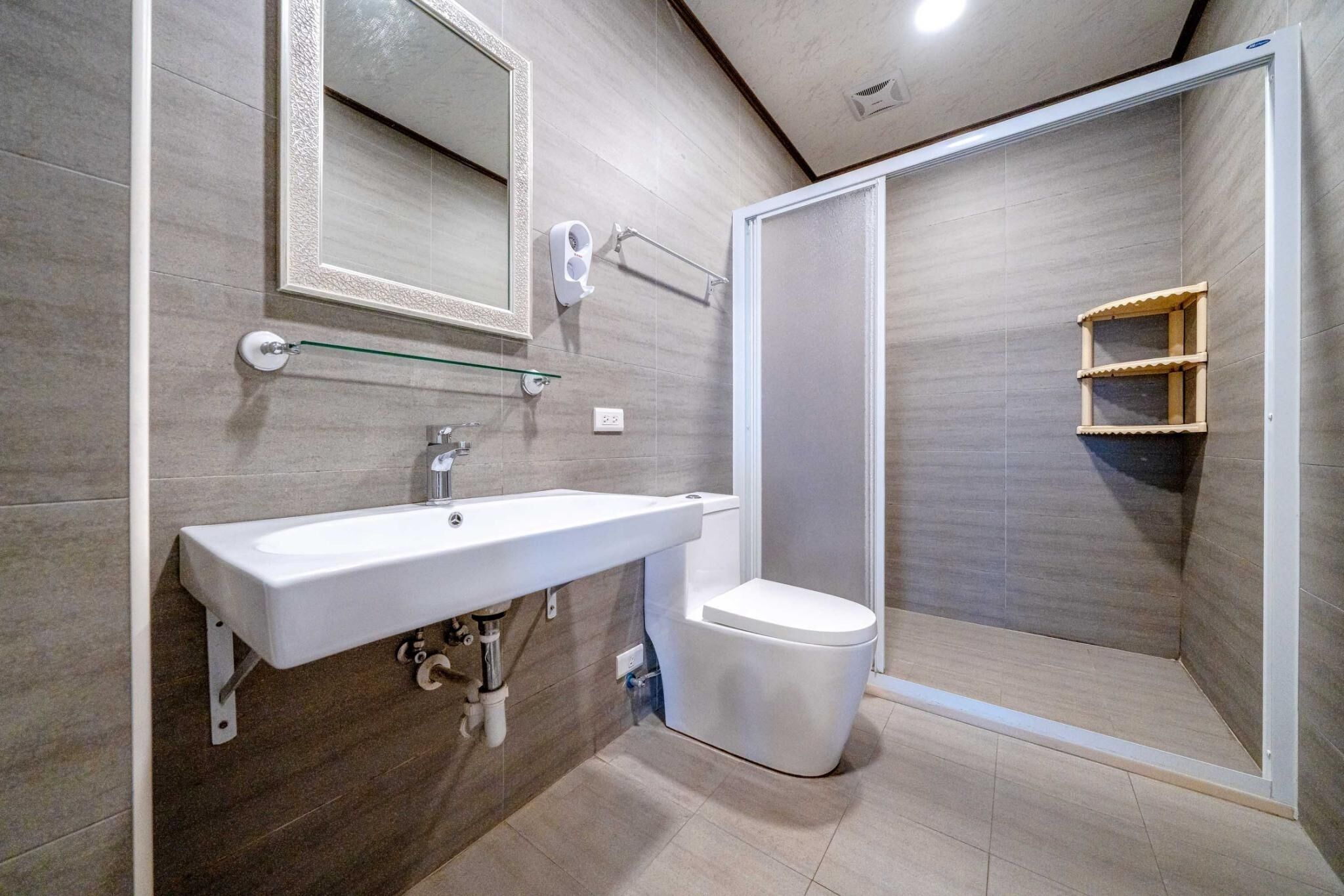 A modern bathroom with a white sink, toilet, and shower enclosure.