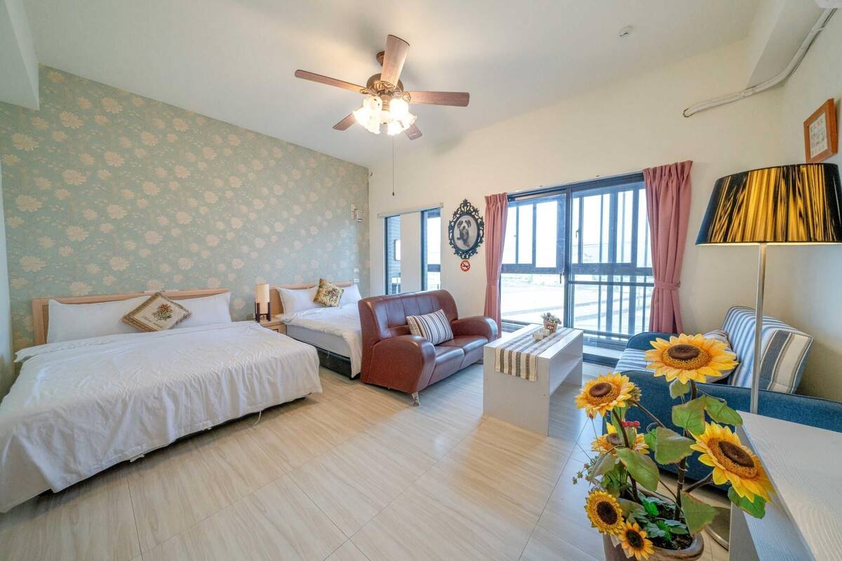 A bedroom with two beds, a sofa, a coffee table, and a ceiling fan.