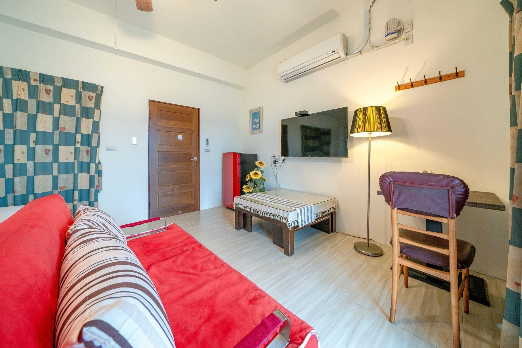 Une pièce comprenant un lit, un bureau, une chaise, un téléviseur et une lampe.
