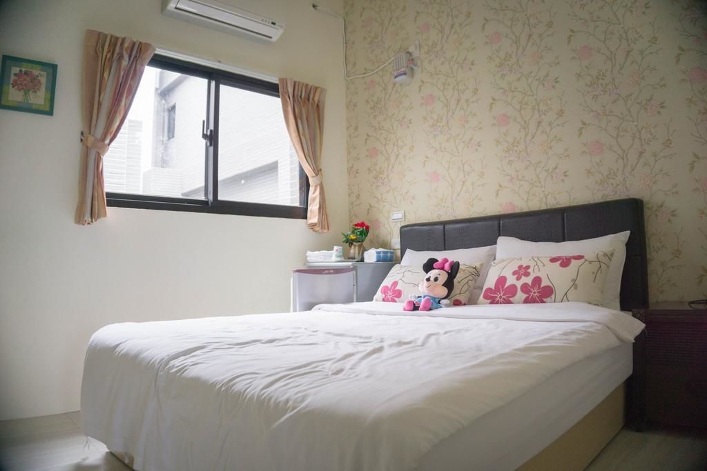 Una cama bien hecha con ropa blanca, cabecera y un peluche de Mickey Mouse.
