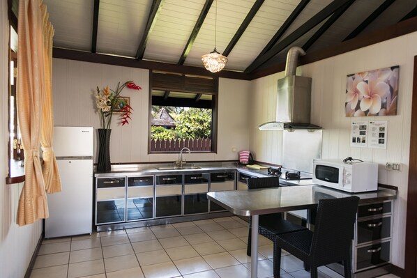 A modern kitchen with a stainless steel countertop, a built-in microwave, and a window with a view of greenery. - Moorea Golf Lodge (Moorea-Maiao)
