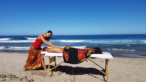 Une séance de massage en plein air, sur une plage avec vue sur l’océan.