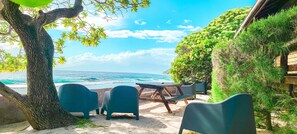 A beachside seating area with a table and chairs, overlooking the ocean. - Moorea Golf Lodge (Moorea-Maiao)