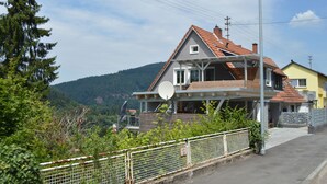 Une maison avec un toit en pente, une antenne parabolique et une cour clôturée.