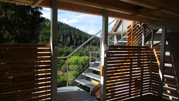 Un balcon donnant sur une colline boisée.