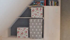Un petit escalier en bois, doté d’étagères où sont rangés des livres et des boîtes décoratives.