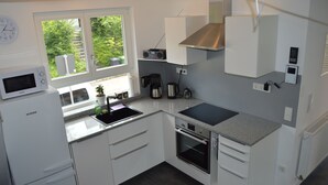 Une cuisine moderne avec des meubles blancs, un four à micro-ondes, une cuisinière et une machine à café.