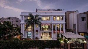 A multi-story building with balconies, a gated entrance, and a well-lit facade. - Palm34 (Jaipur)