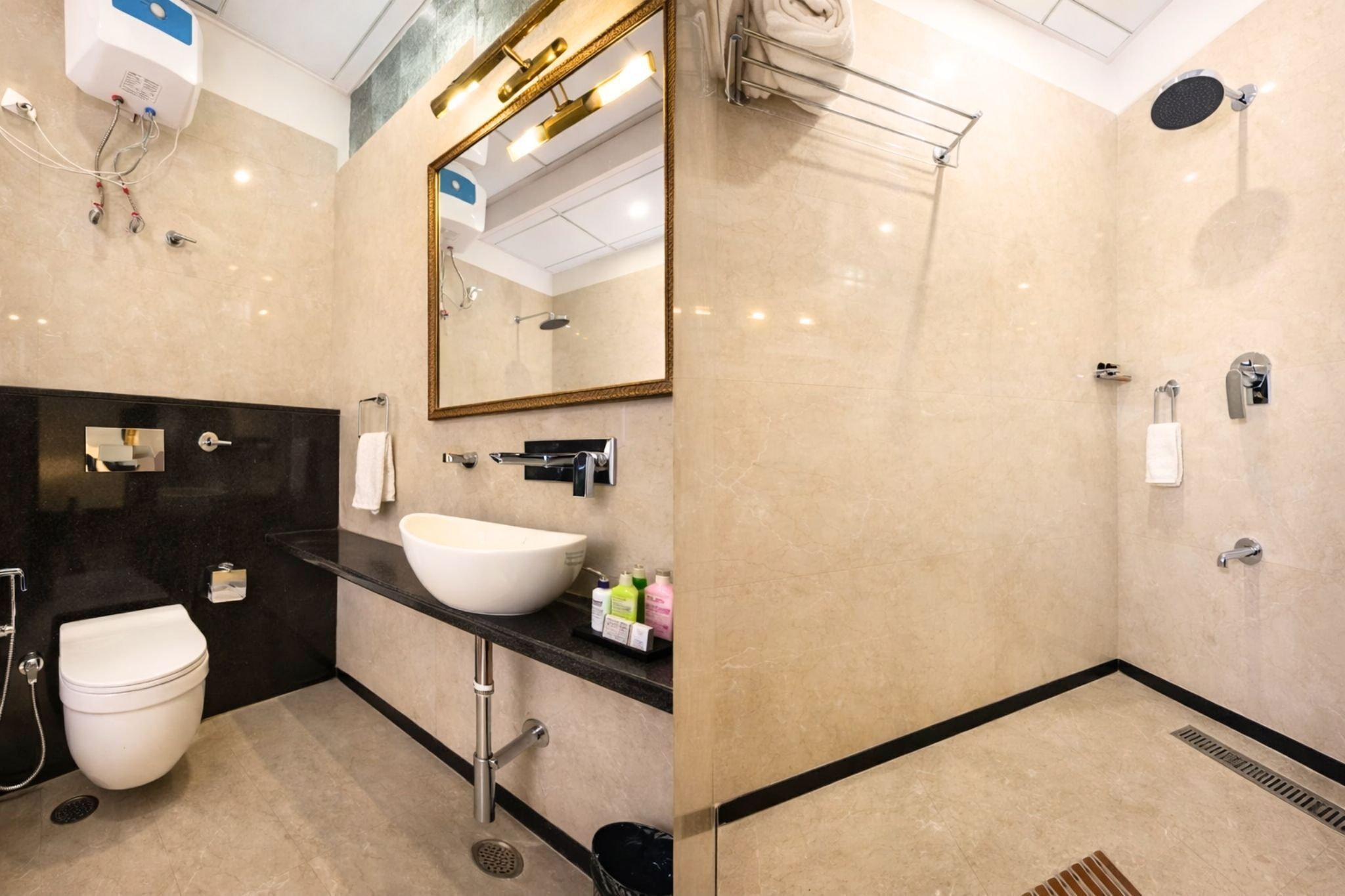 Un baño moderno con un espejo grande, un lavamanos blanco, una ducha y un inodoro.