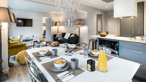 Una cocina moderna con una isla central, una mesa de comedor y una lámpara de araña.