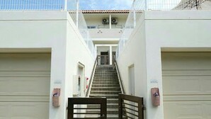 A narrow, enclosed stairway leading to a building with a flat roof and a white exterior. - Sea Side Yaka (Kin)
