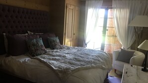A bedroom with a large bed, a wooden headboard, and a nightstand with a lamp. - Villars sur Ollon Luxury chalet 600m2 (Villars-sur-Ollon)