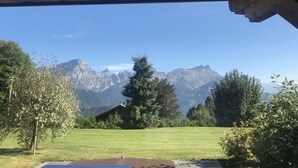 A view of a mountain range from a covered outdoor area with a grassy field in the foreground. - Villars sur Ollon Luxury chalet 600m2 (Villars-sur-Ollon)