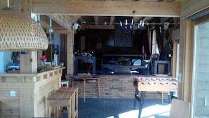 A rustic wooden interior with a brick fireplace, wooden furniture, and a foosball table.