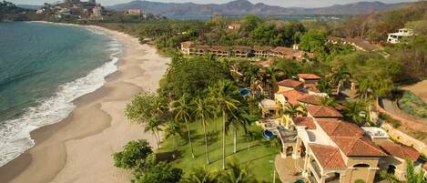 A coastal resort with beachfront villas, a swimming pool, and lush greenery.