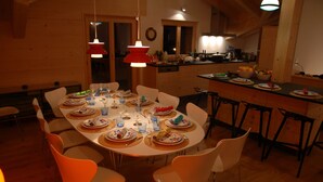 A dining area with a round table set for a meal, surrounded by chairs. - eco-Chalet in Les Crosets (Valais)
