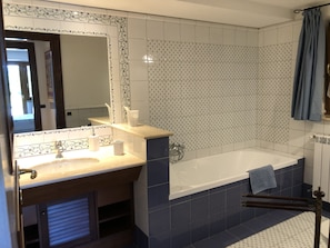 Un baño con lavamanos, espejo y bañera.
