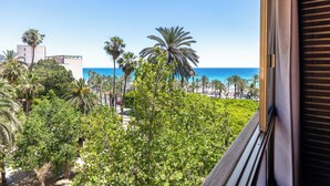 A balcony with a view of the ocean, palm trees, and buildings.