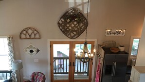 A cozy interior with a wooden ceiling, a dining area with a table and chairs, a kitchen with a refrigerator, and a view through the glass doors. - Ridge Cottage Residence (Campobello)