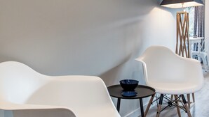 Un interno moderno con sedie bianche, un tavolino rotondo e una lampada da terra.