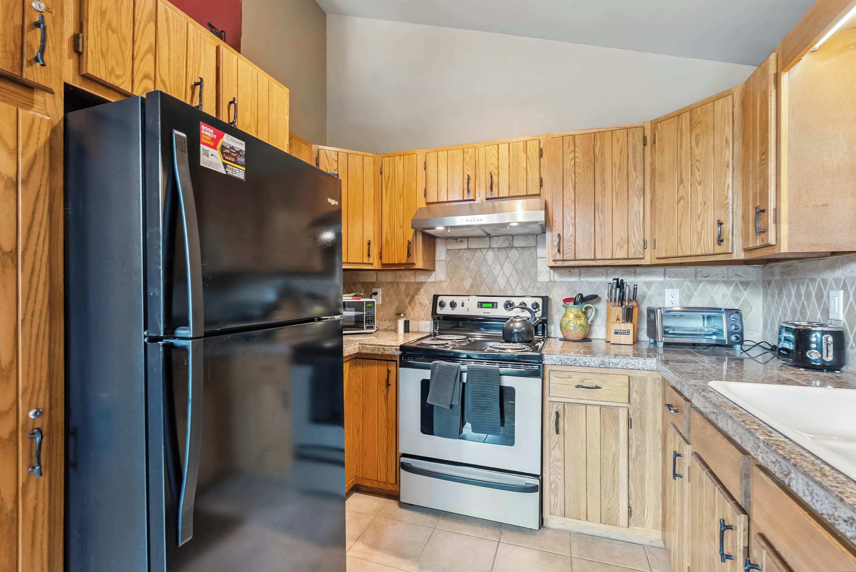 A kitchen with wooden cabinets, a black refrigerator, a stove, and a microwave.