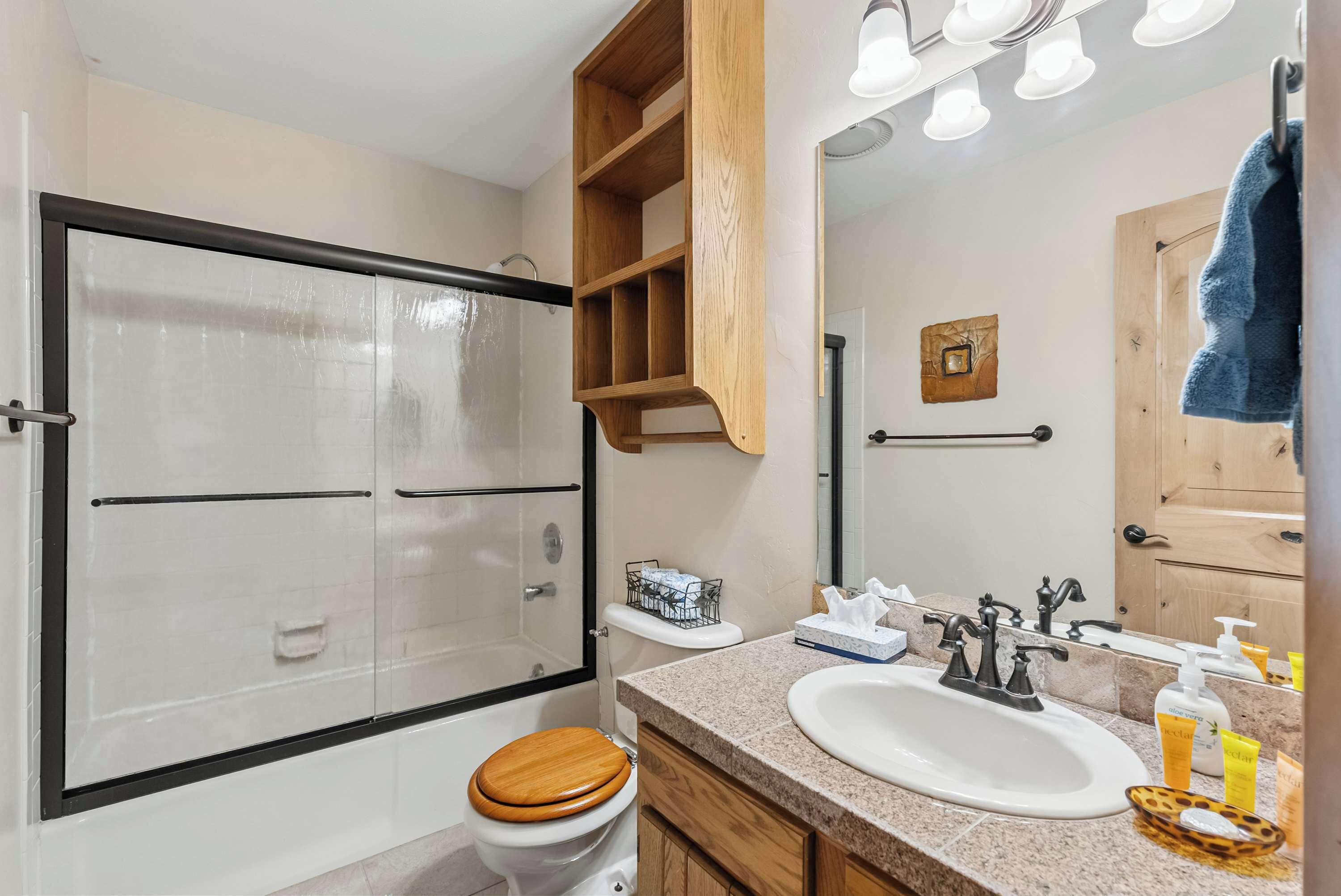 A bathroom with a shower, toilet, vanity, and a mirror.