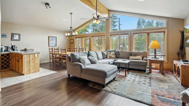 A spacious living area with a large sectional sofa, a dining table, and a kitchen area with wooden cabinets.