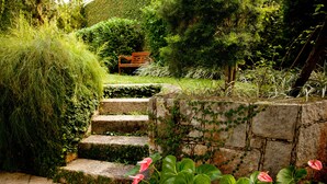 A stone staircase surrounded by lush greenery and pink flowers. - São Conrado Classy (Rio de Janeiro)