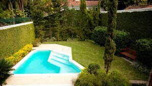 A rectangular swimming pool with a tiled deck, surrounded by well-maintained grass and various shrubs. - São Conrado Classy (Rio de Janeiro)