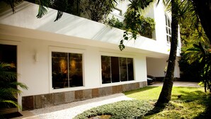 A modern building with large windows, a well-maintained lawn, and a tree. - São Conrado Classy (Rio de Janeiro)